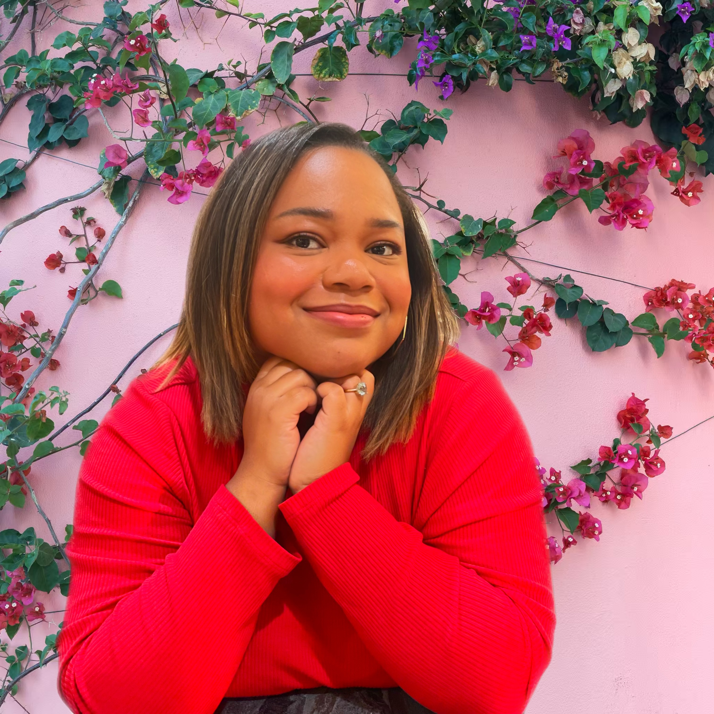 A woman smiles in front of an ivy wall.